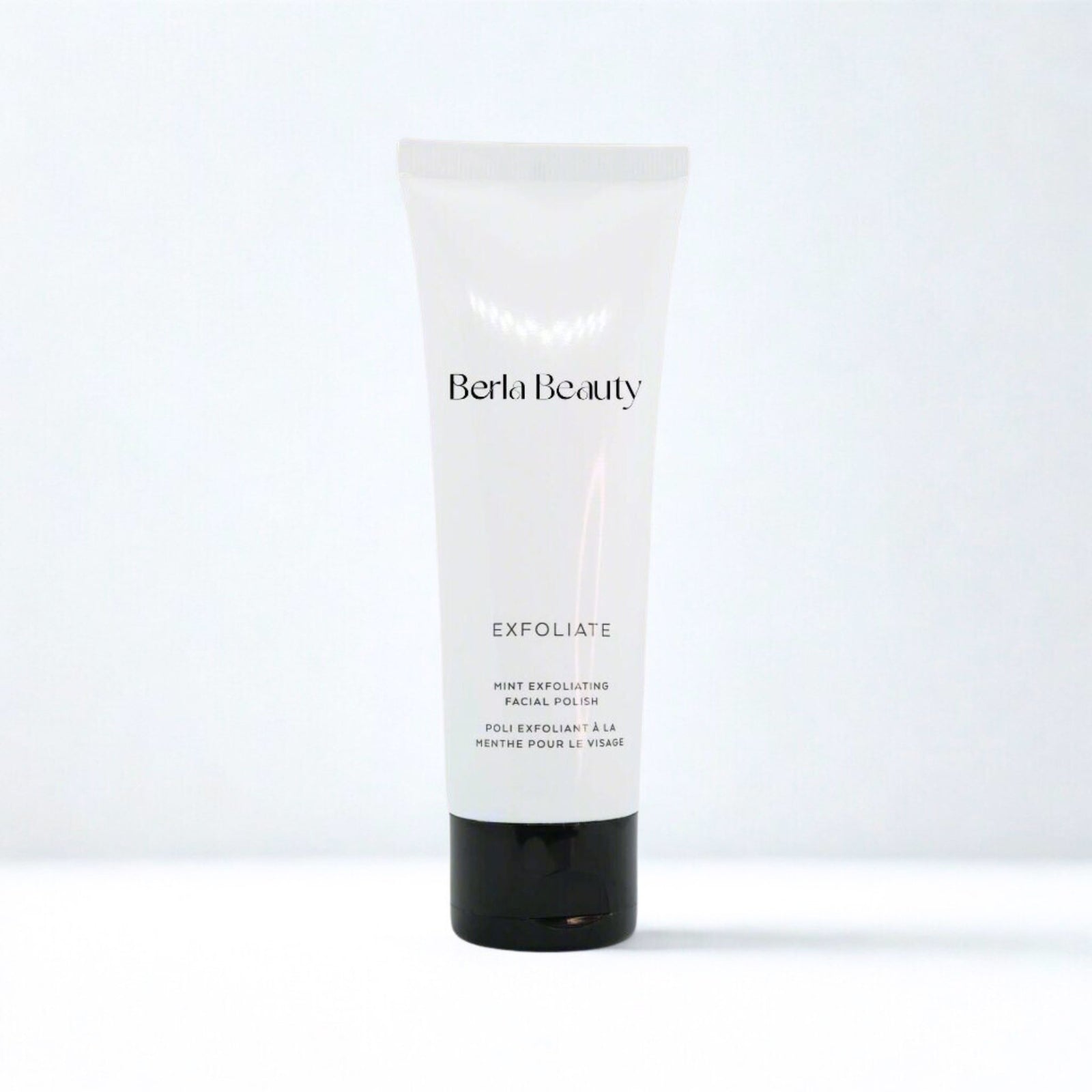A tube of Berla Beauty Mint Exfoliating Facial Polish stands against a neutral background. The product, labeled "Mint Exfoliating Facial Polish with Apricot Oil," is designed for facial use. The tube features a simple, clean design with black and white text.