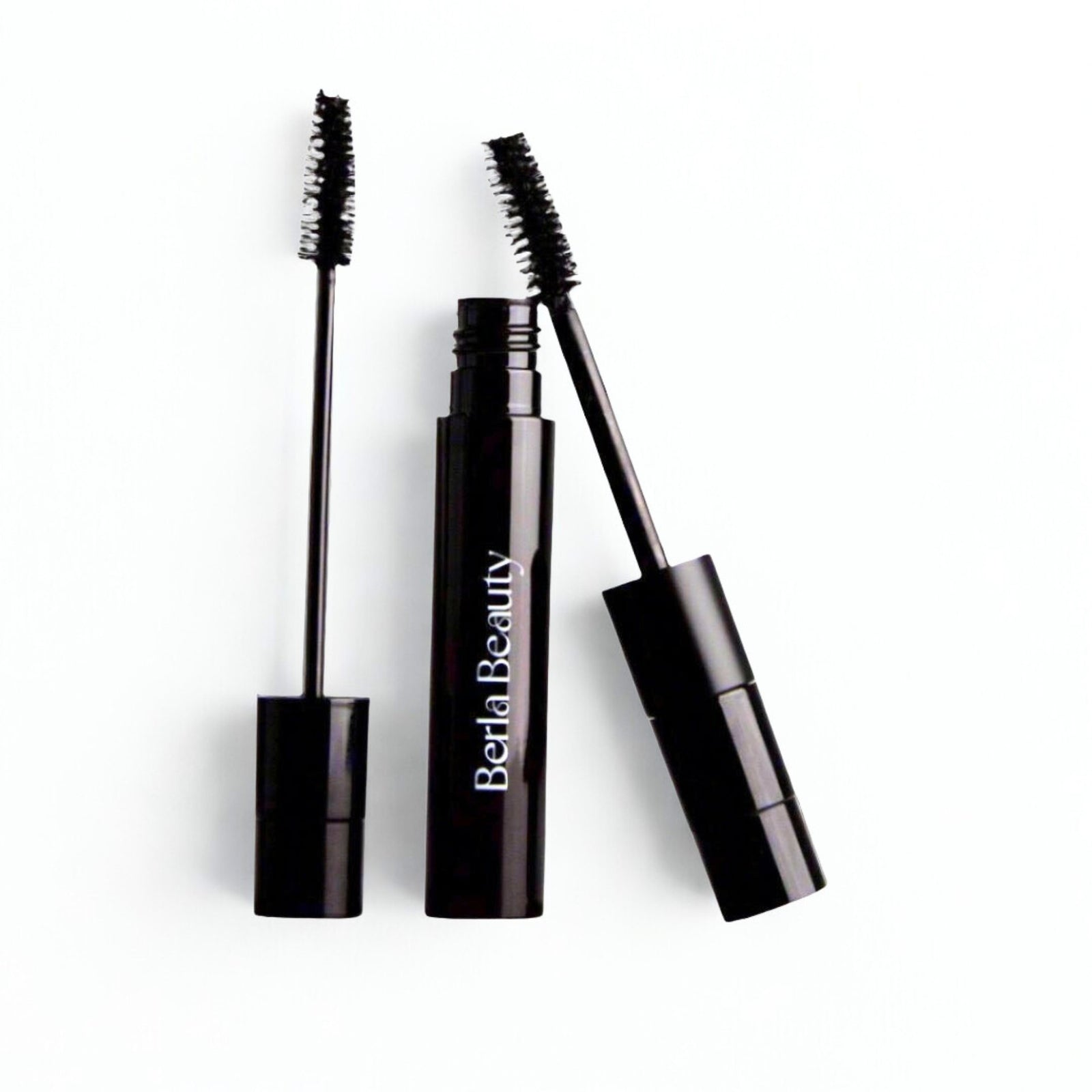 Three black mascara tubes from Berla Beauty are shown, with one open to reveal its mascara wand. The design is sleek and minimalist, featuring the brand name "Berla Beauty" in white letters on the tube. Notably, this "Vegan Dual Lash Long Lasting Mascara - Bold and Beautiful Lashes" boasts a lightweight formula that is both vegan and cruelty-free.