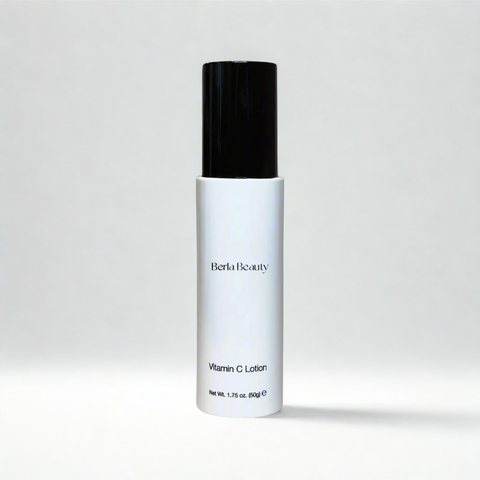 A sleek white bottle with a black cap, labeled "Berla Beauty" and "Vitamin C Lotion," boasts a clean, minimalist design against a plain beige background. This 1.75 oz (50 grams) product promises to brighten the skin while providing deep hydration.